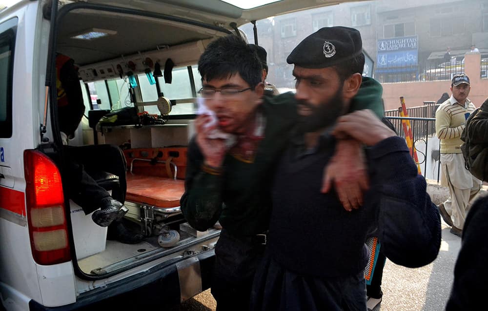A hospital security guard helps a student injured in the shootout at a school under attack by Taliban gunmen in Peshawar, Pakistan.