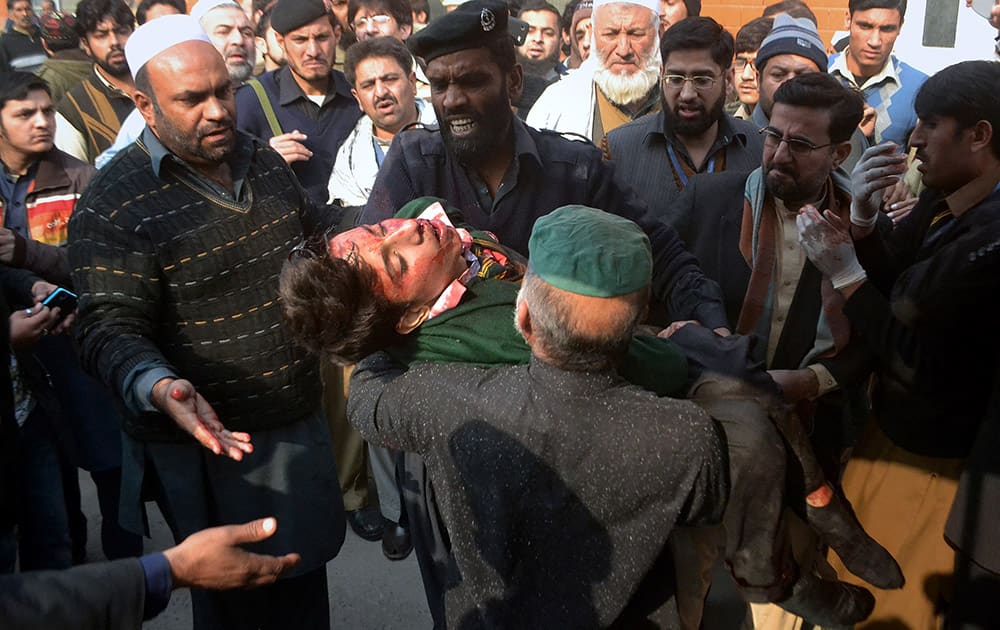 Hospital security guards carry a students injured in the shootout at a school under attacked by Taliban gunmen in Peshawar, Pakistan.