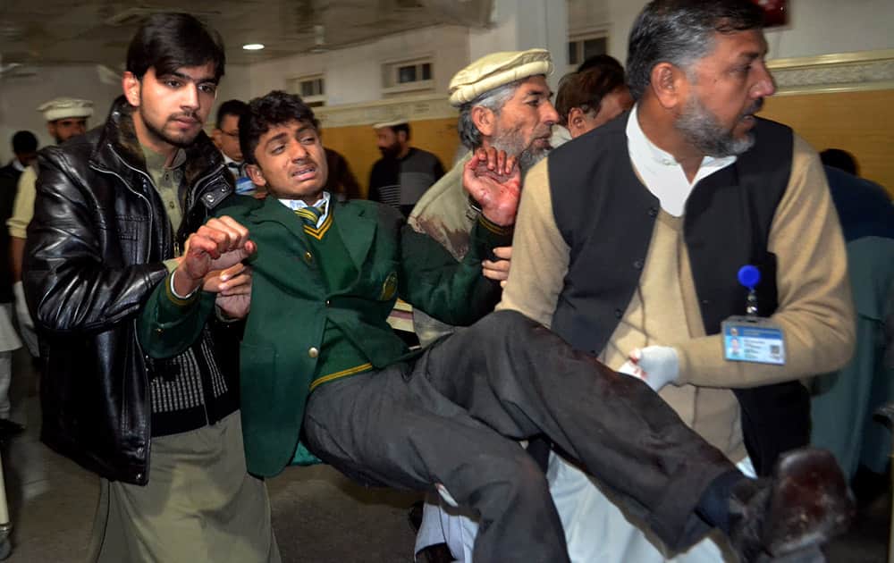Pakistani volunteers carry a student injured in the shootout at a school under attack by Taliban gunmen, at a local hospital in Peshawar, Pakistan.
