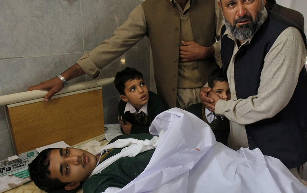 A Pakistani man comforts a student standing at the bedside of a boy who was injured in a Taliban attack on a school, at a local hospital in Peshawar, Pakistan.
