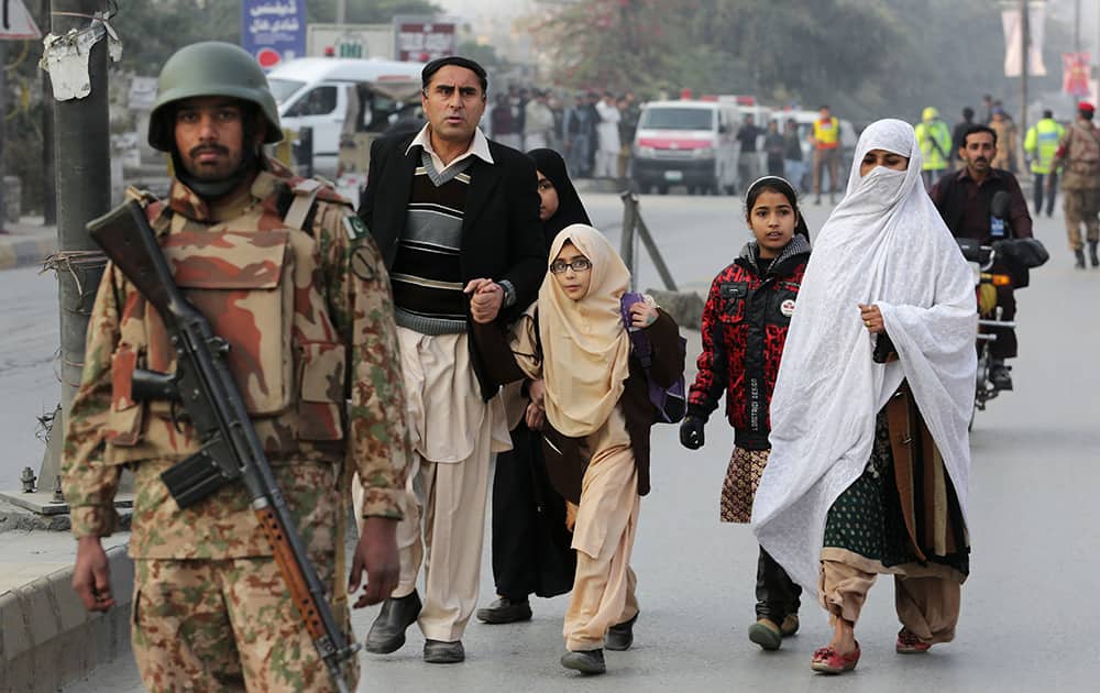 Pakistani parents escort their children outside a school attacked by the Taliban in Peshawar, Pakistan.
