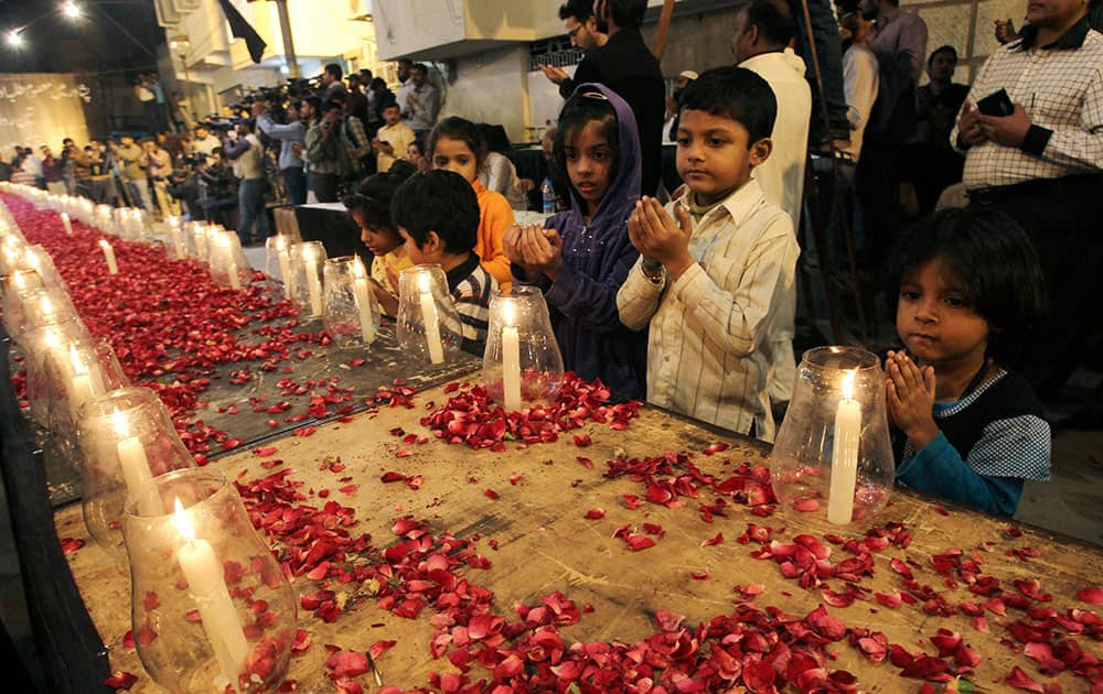 Pakistani children, chant prayers, during a candle light vigil for the victims of a Taliban attack on a school in Peshawar, organized by supporters of the Mutahida Qaumi Movement (MQM), in Karachi, Pakistan.