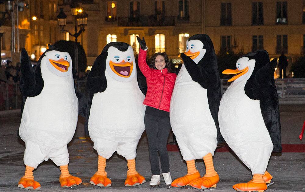 French ice skater Nathalie Pechalat poses with people wearing penguin costumes, as she takes part in the launch of the movie 'Penguins of Madagascar', at the ice rink, in front of the Paris City Hall, in Paris.