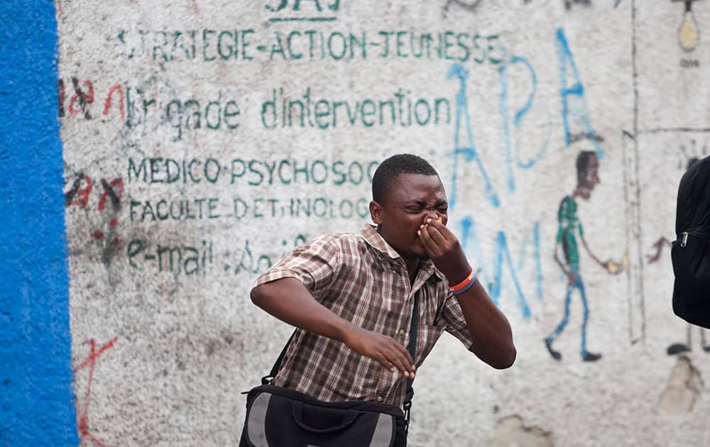 An anti-government demonstrator runs away from tear gas during a protest calling for the resignation of Haiti's President Michel Martelly in Port-au-Prince, Haiti.