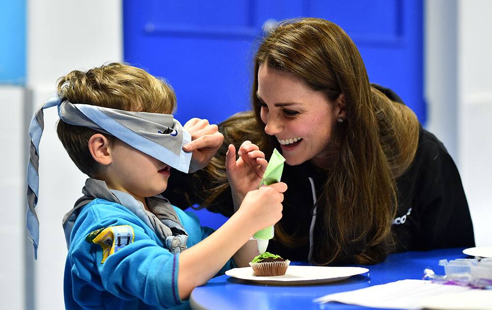Britain's Kate, Duchess of Cambridge checks the blindfold of Fynley Gooch, 7, before helping him ice a cake as she promotes disability awareness as she meets with children at the newly established 23rd Poplar Beaver Scout Colony in east London.