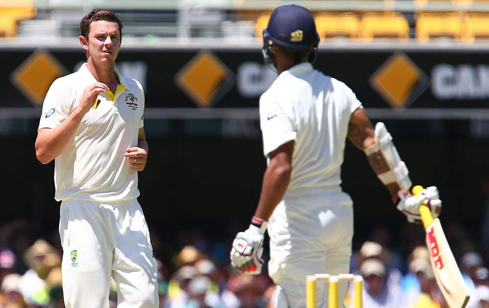 Australian fast bowler Josh Hazelwood, left, looks at India's Shikhar Dhawan during the second cricket test match between Australia and India in Brisbane, Australia