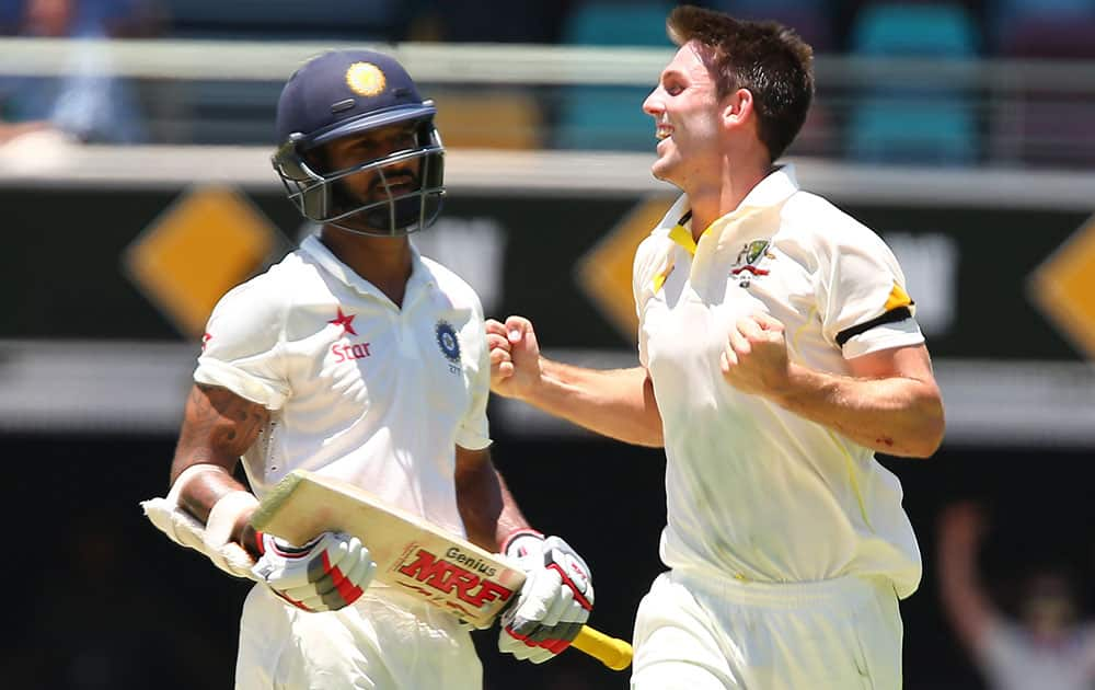 Australia's Mitchell Marsh celebrates after taking the wicket of India's Shikhar Dhawan, left, during the second cricket test match between Australia and India in Brisbane, Australia.