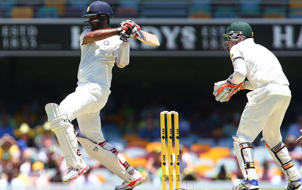 Indian batsman Cheteshwar Pujara plays a pull shot as Australia's Brad Haddin, right, looks on during the second cricket test in Brisbane, Australia.