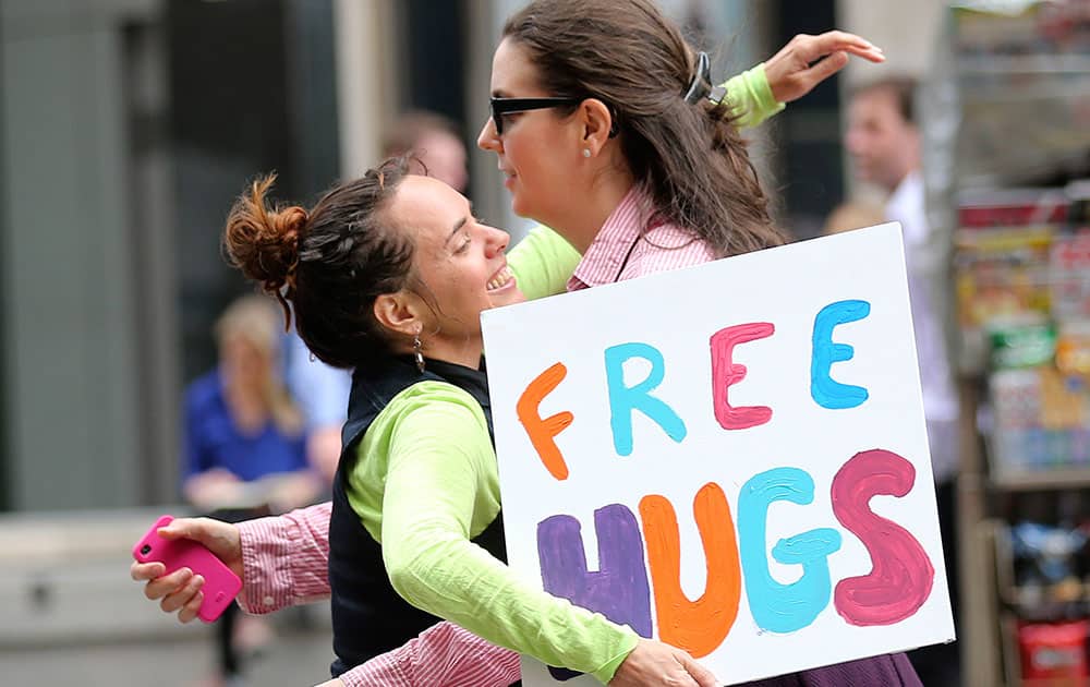 Michelle Cotterill gives a woman a hug in the street at a temporary memorial site close to the Lindt cafe in the central business district of Sydney, Australia.