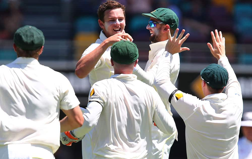 Australia's Josh Hazelwood is congratulated by teammates after taking the wicket of India's Cheteshwar Pujara during the second cricket test match in Brisbane, Australia.