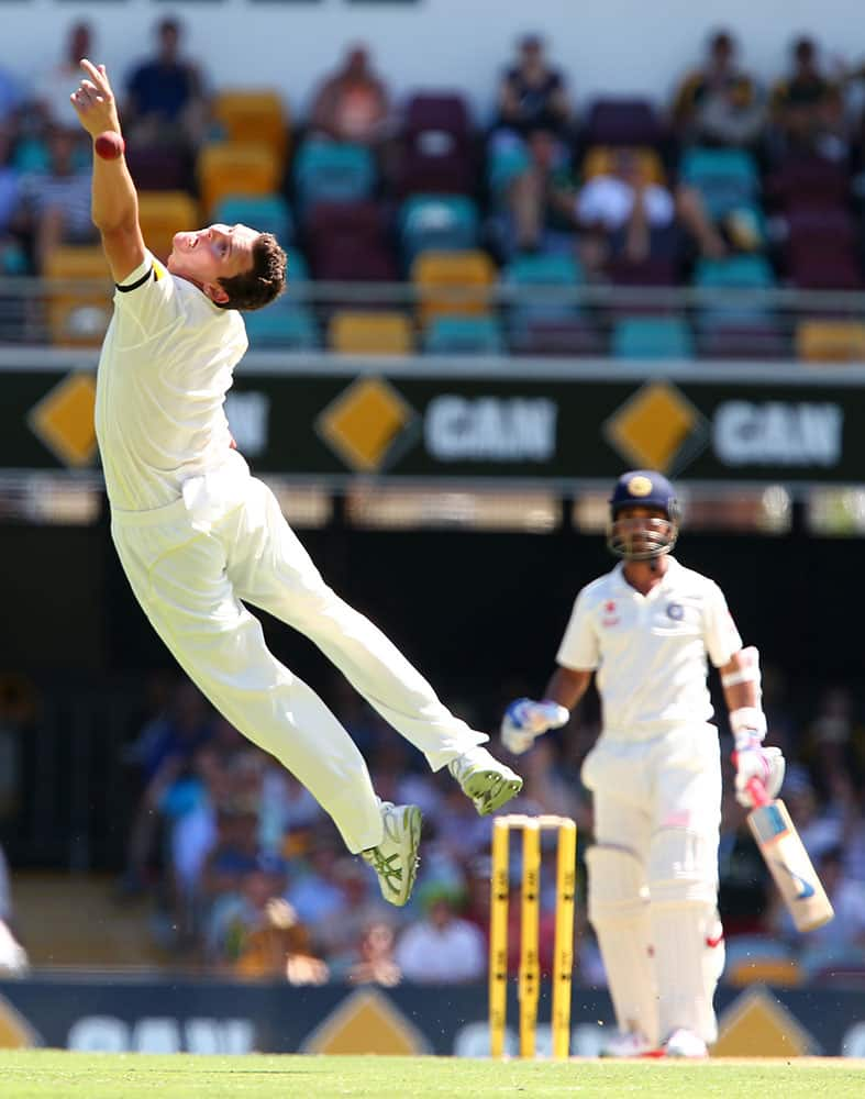 Australia's Josh Hazelwood is airborne as he attempts to take a catch off Indian batsman Ajinkya Rahane, right, during the second cricket test match in Brisbane, Australia.