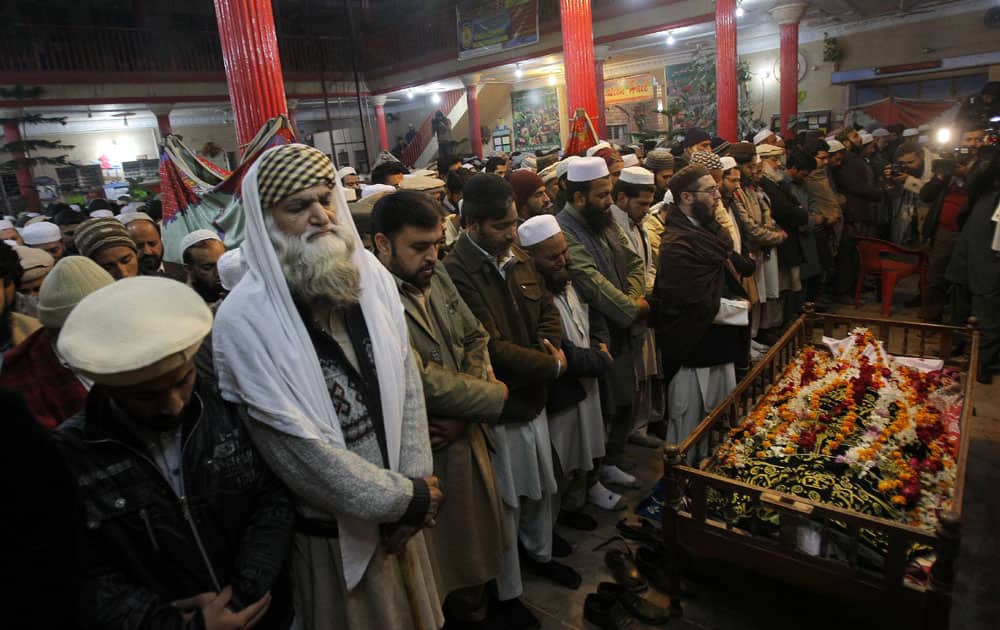 Mourners and relatives of Pakistani teacher, Saeed Khan, a victim of a Taliban attack in a school, pray around his body, during his funeral procession in Peshawar, Pakistan.