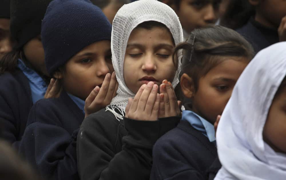 Pakistani students pray during a special ceremony for the victims of Tuesday's school attack in Peshawar, at a school in Lahore, Pakistan.