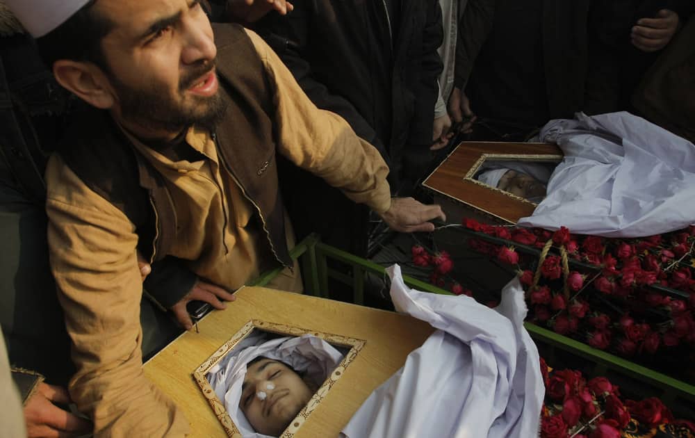 A family member of students killed in Tuesday's Taliban attack on a school prepares for their burial in Peshawar, Pakistan.