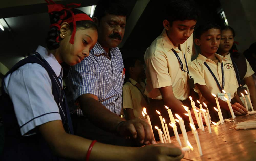 India school children and officials light candles in memory of victims killed in a Taliban attack on a military-run school in Peshawar, at a school in Mumbai, India.