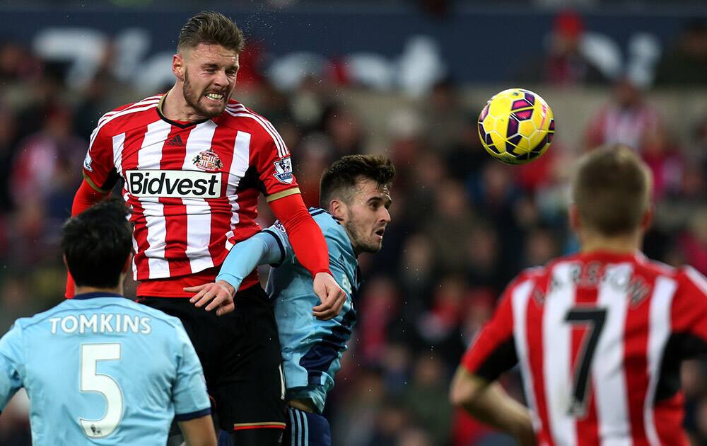 Sunderland's Connor Wickham, top, vies for the ball with West Ham United's James Tomkins, left, and Carl Jenkinson, center, during their English Premier League soccer match at the Stadium of Light, Sunderland, England.