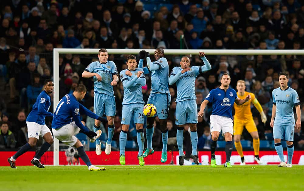 Manchester City players including Yaya Toure, centre, jump to block a fee kick by Everton's Kevin Mirallas, second left, during the English Premier League soccer match between Manchester City and Everton at the Etihad Stadium, Manchester, England.