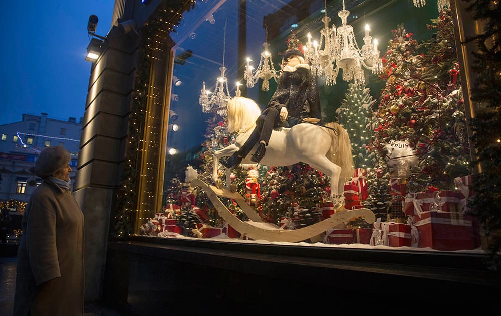 An elderly woman looks at a decorated for Christmas shop window of the Central Department Store in downtown Moscow, Russia.