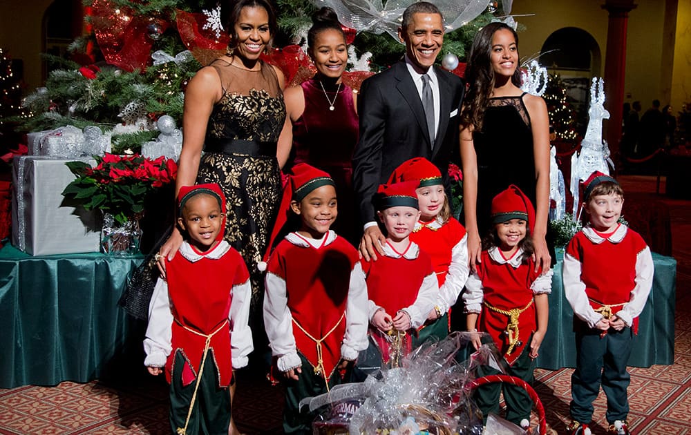 The first family, first lady Michelle Obama, Sasha Obama, President Barack Obama and Malia Obama, pose with children dressed like elves at the National Building Museum in Washington.