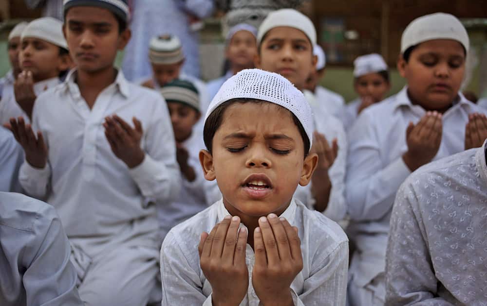 Muslim children pray at a madrasa, or religious school, for Tuesday's Taliban attack victims in Peshawar, in Ahmedabad.