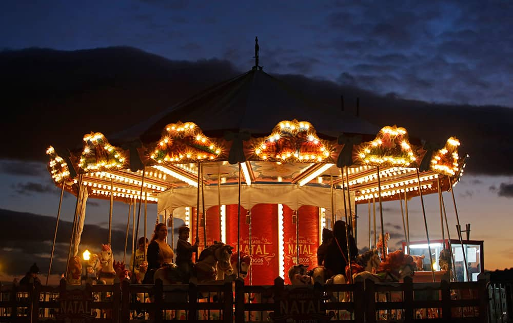 People ride on a carousel in a Christmas market at the Comercio square, in Lisbon, Portugal.