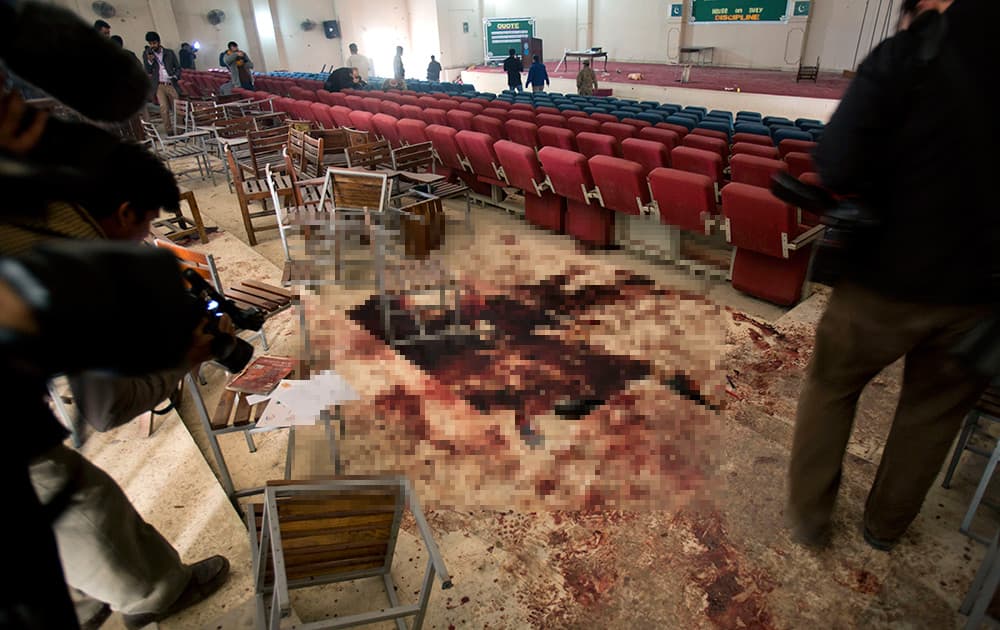 Pakistani video journalists film inside the auditorium of an Army Public School a day after an attack by the Taliban, in Peshawar, Pakistan.