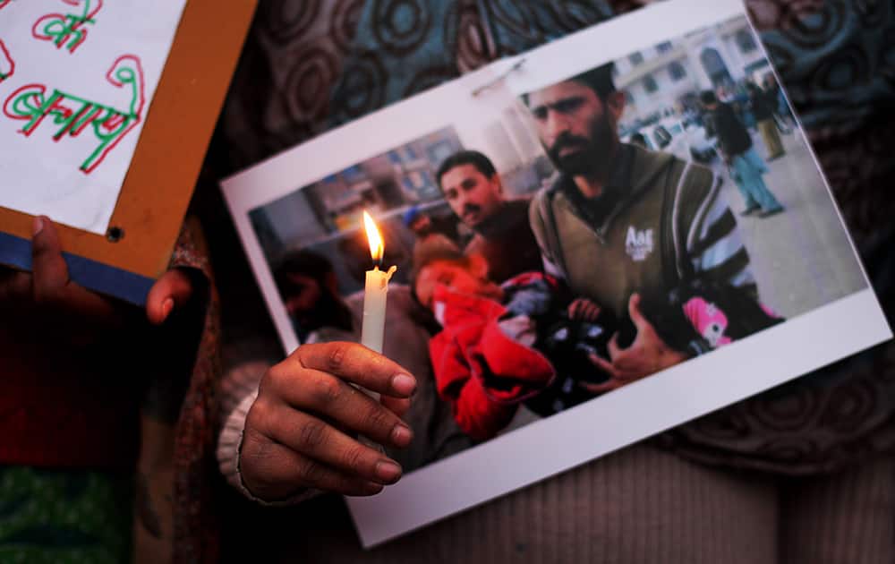 An Indian holds a candle and a photograph of a wounded child during a candlelight vigil in memory of the victims of Tuesday's Taliban attack in Peshawar, in New Delhi.