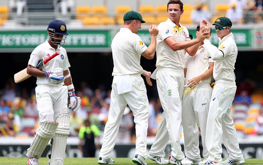 Australia's Josh Hazlewood is congratulated by teammates after taking the wicket of India's Ajinkya Rahane, left, during play on day two of the second cricket test in Brisbane, Australia.