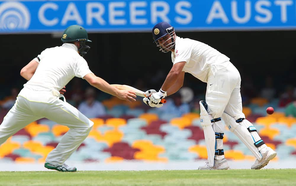 India's MS Dhoni plays a shot as Australia's Chris Rogers looks to chase during play on day two of the second cricket test in Brisbane, Australia.