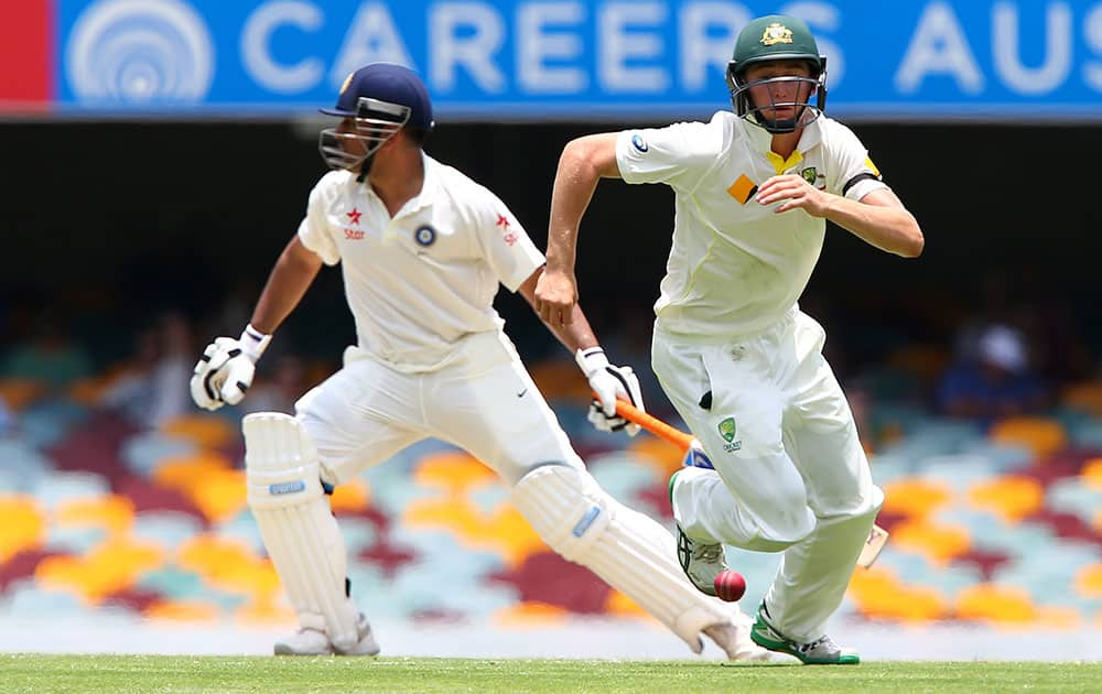 Australian fielder Chris Rogers runs after the ball played by India's MS Dhoni during play on day two of the second cricket test in Brisbane, Australia.