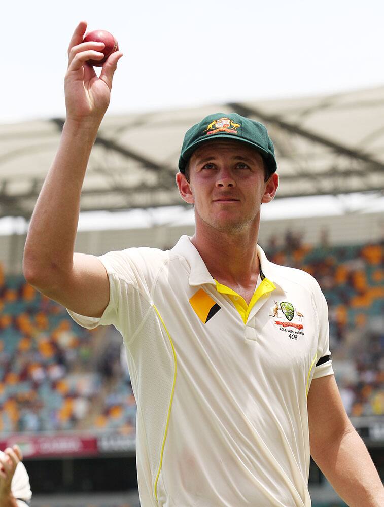 Australian bowler Josh Hazlewood holds the ball aloft after taking five wickets on debut during play on day two of the second cricket test against India in Brisbane, Australia.