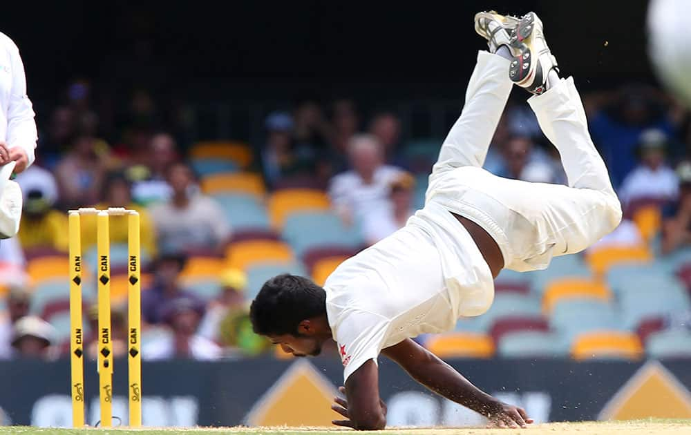 Indian bowler Varun Aaron falls over while bowling to Australian batsman David Warner during play on day two of the second cricket test in Brisbane, Australia.