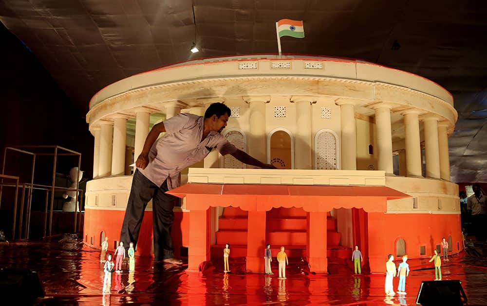 A worker touches a cake made in the shape of Indian parliament building on display at the annual cake show as part of new year celebrations in Bangalore, India.  The cake measures 18 feet in diameter and is made of about 5000 kilogram (11,023 pounds) of sugar, eggs and cornflour, claimed the maker.