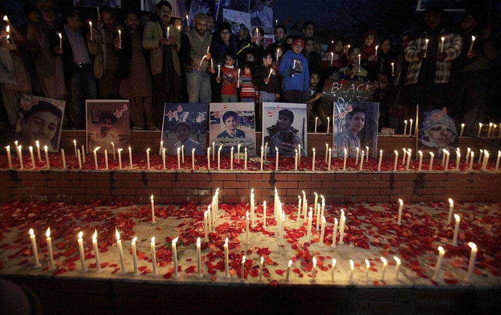 Local residents place candles around portraits of the victims killed in Tuesdays Taliban attack on a military-run school in Peshawar, at a ceremony in Islamabad, Pakistan.