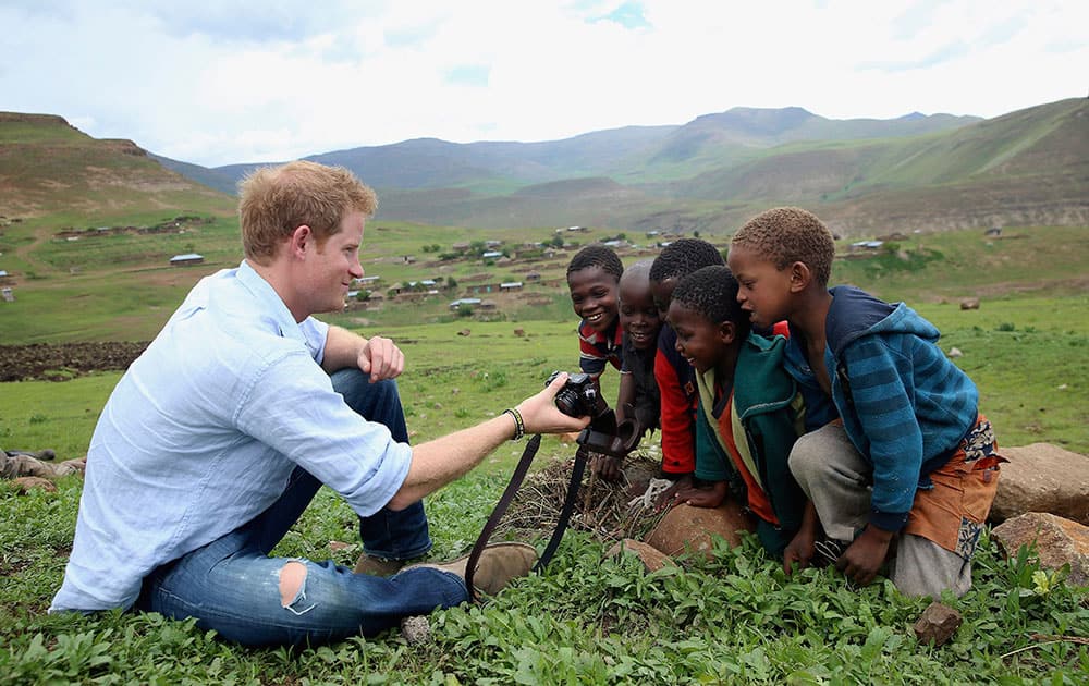 Britain Prince Harry shows children a photograph he has taken during a visit to a herd boy night school constructed by his charity Sentebale in Mokhotlong, Lesotho.