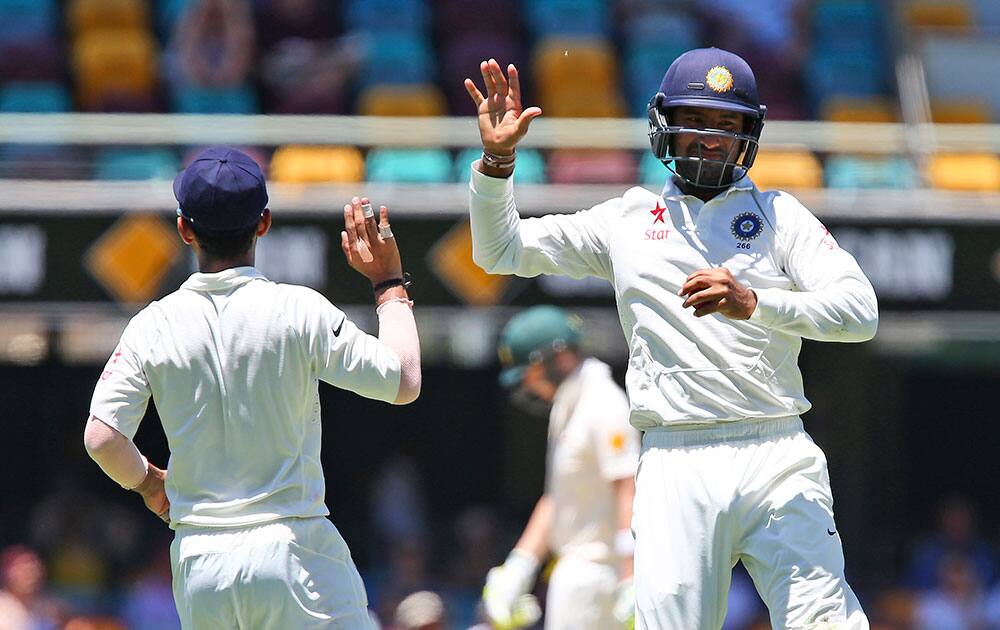 Cheteshwar Pujara, high-fives a team mate after catching out Australia Brad Haddin on the third day of the second cricket test in Brisbane, Australia.