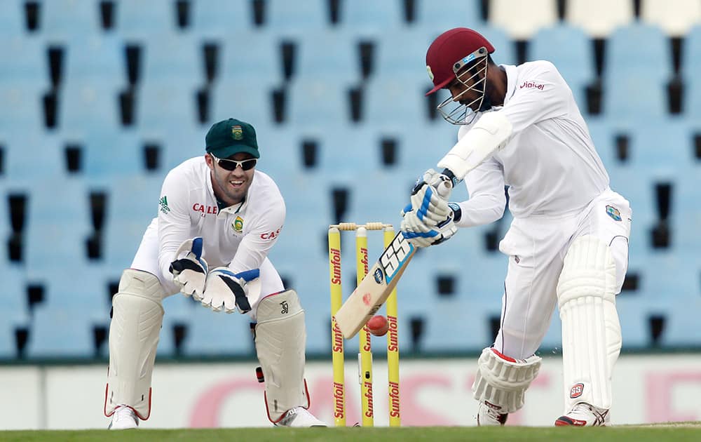 West Indies captain Denesh Ramdin, plays a shot as South Africa’s AB de Villiers watches during their third day of their 1st cricket test match at Centurion Park in Pretoria, South Africa.