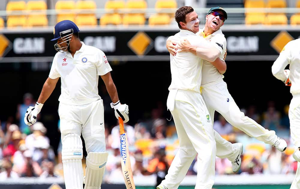 Australia's Josh Hazlewood, celebrates with David Warner, after getting the wicket of MS Dhoni, during their match on day four of the second cricket test in Brisbane, Australia.