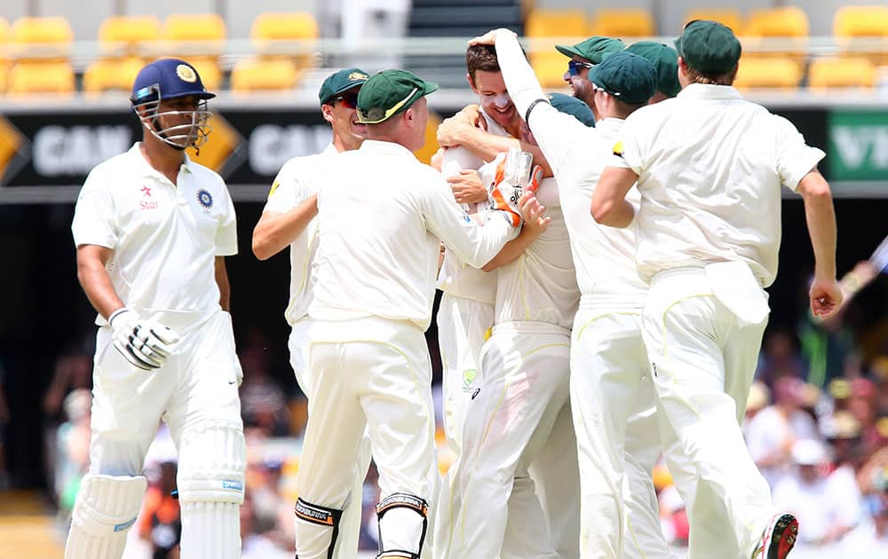 Australia's Josh Hazlewood, celebrates with his teammates after getting the wicket of MS Dhoni, at their play on day four of the second cricket test in Brisbane, Australia.