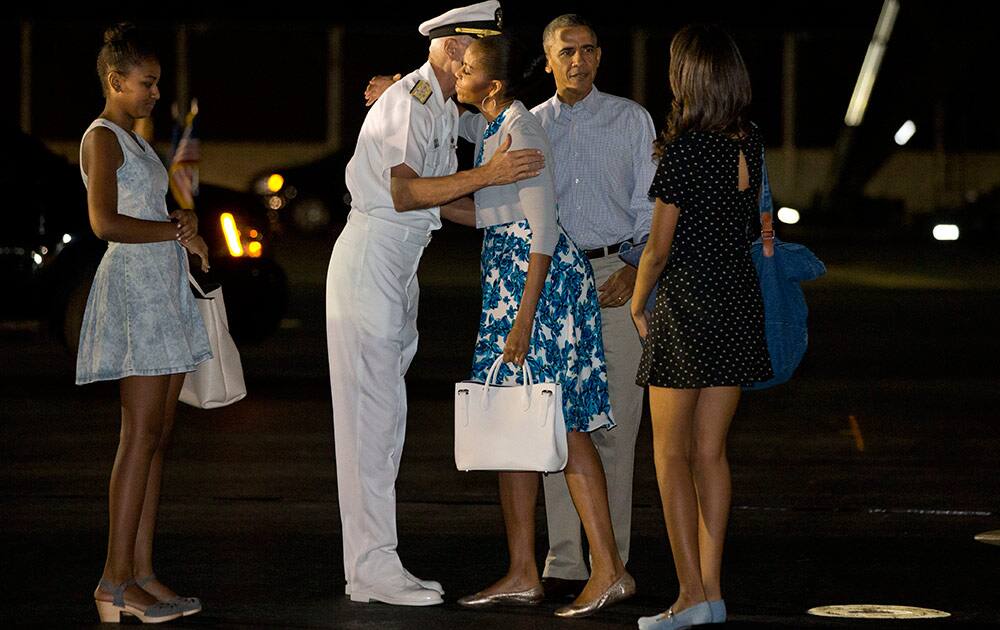 First lady Michelle Obama hugs Admiral Samuel Locklear III, Commander, U.S. Pacific Command, with daughter Sasha Obama, and Malia Obama, and President Barack Obama as the first family arrives at Pearl Harbor, Hawaii to begin their family vacation.