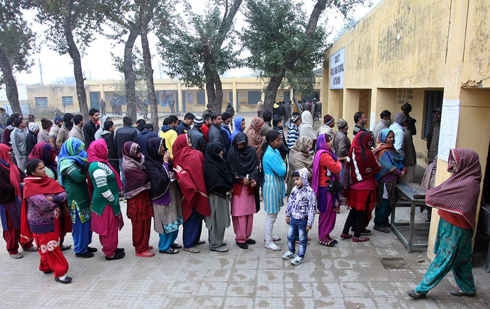 People stand in queues to cast their votes outside a polling station during the fifth phase of voting, at Satrayan, Jammu.