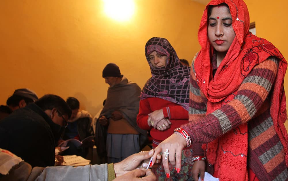 A polling officer marks the finger of a voter with indelible ink inside a polling station during the fifth phase of voting, at Satrayan village, Jammu.