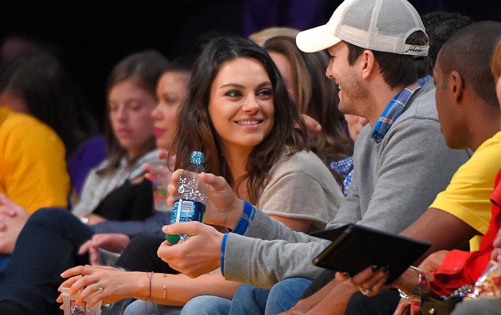 Actors Mila Kunis and Ashton Kutcher watch the Los Angeles Lakers play the Oklahoma City Thunder in an NBA basketball game, in Los Angeles.