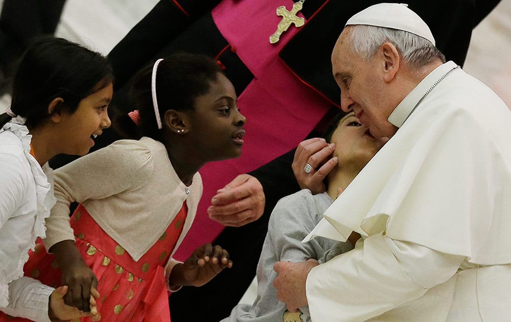 Pope Francis kisses a child during a meeting with faithful of Pope John XXIII Community in the Paul VI hall at the Vatican.