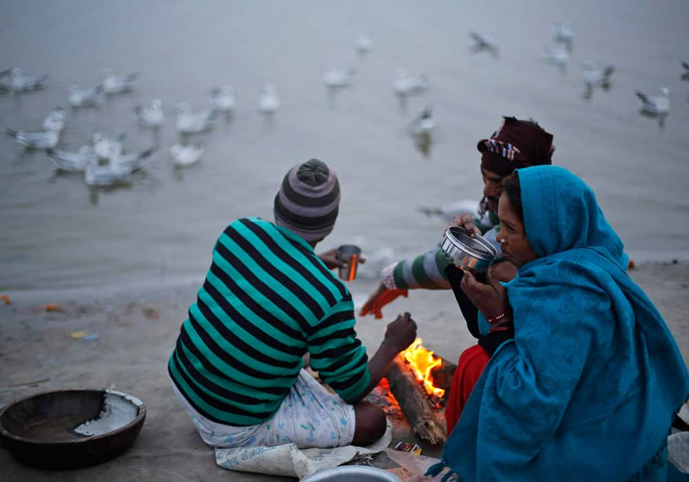 Indian street vendors keep warm around a bonfire on a cold evening on the banks of the River Ganges in Allahabad.