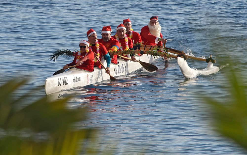 People dressed in Santa Claus costumes in a canoe, take part to the traditional Christmas bath in Monaco, Sunday.