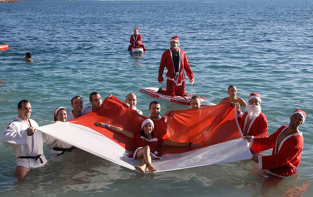 Swimmers pose for photographers with a Monaco flag, Sunday,during the traditional Christmas bath in Monaco.