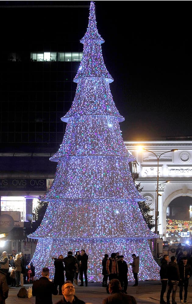 People stand near the illuminated Christmas tree set on the main square in Macedonia’s capital Skopje.