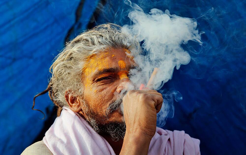 A Sadhu, or Hindu holy man, smokes marijuana to stay warm at Sangam, the confluence of rivers Ganges, Yamuna and mythical Saraswati in Allahabad, India.