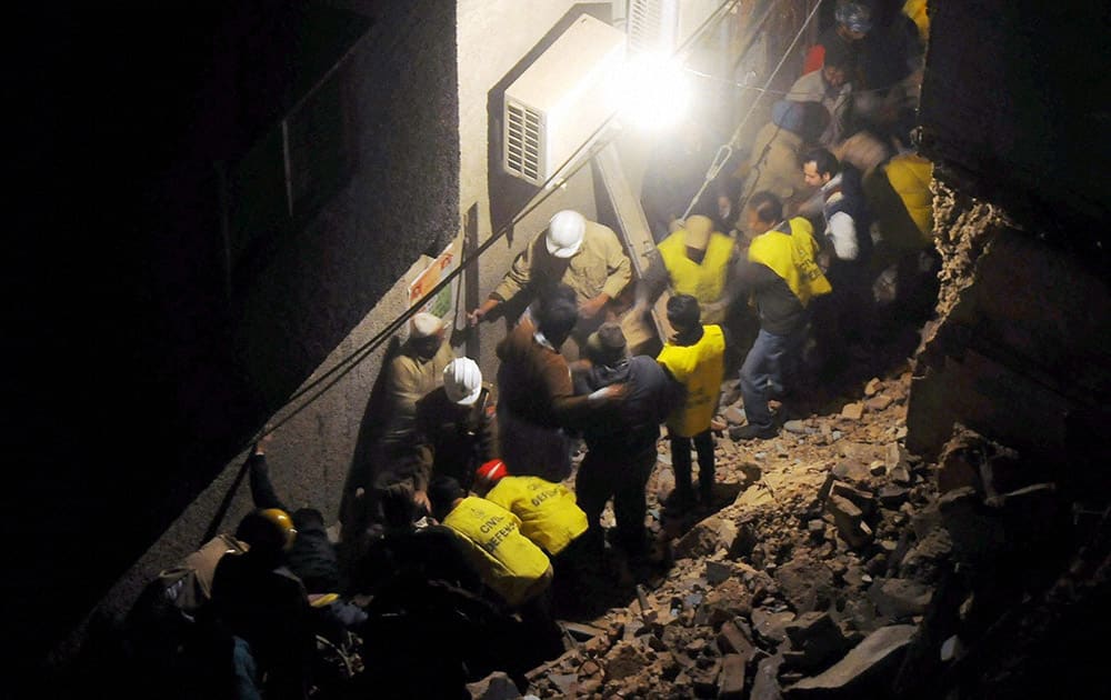 Police and locals at work after a building collapsed in Walled City area in New Delhi.